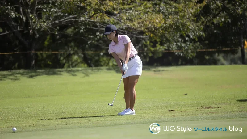 アプローチ練習エリアでチッパーのフォロースルーポーズを保つ30代女性