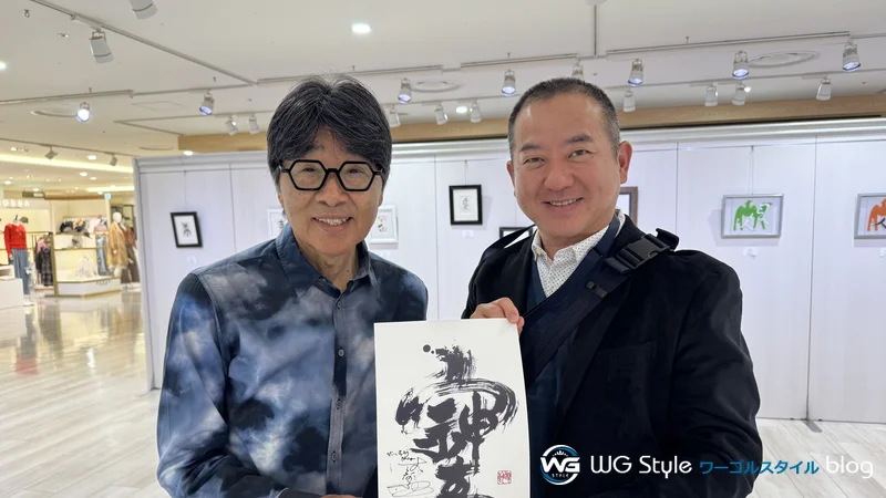 原田伸郎さんと直筆サインを手にするワールドゴルフスタッフ