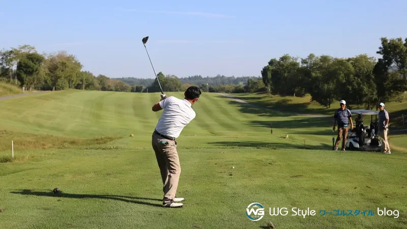 朝のゴルフコース1番ホールで初めてのティーショットに臨む30代男性