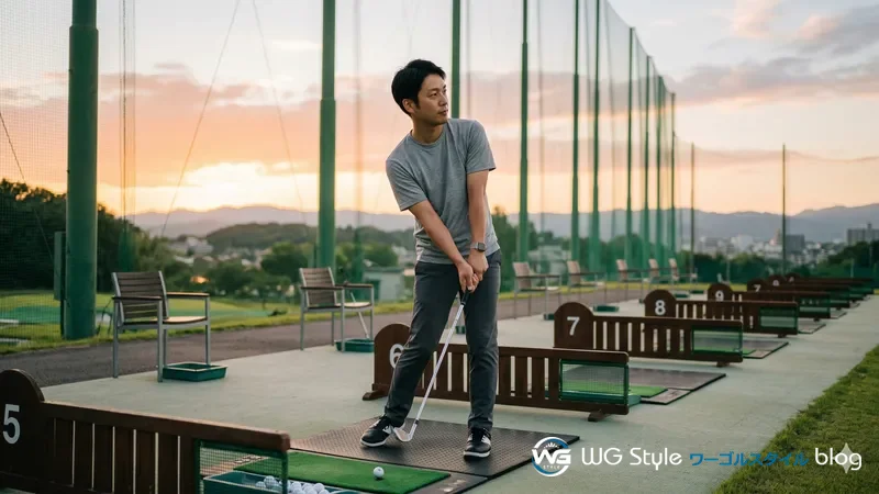 夕方の屋外練習場で周囲の打席が空の中、1人でアイアンスイングに集中する30代男性