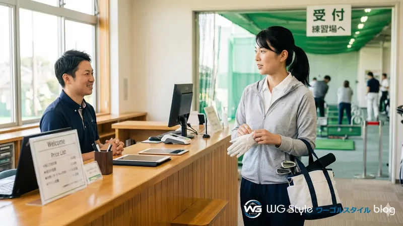 練習場の受付でゴルフグローブを装着しながらスタッフに声をかけている30代女性