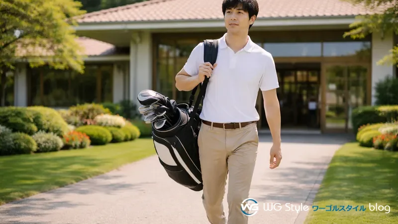 白ポロシャツとチノパン姿の30代日本人男性がゴルフ場のクラブハウス入口に向かって歩く