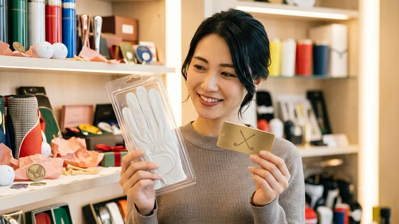 ゴルフショップでプレゼント用のゴルフグッズを選んでいる女性
