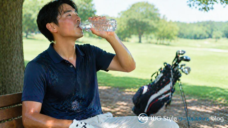 真夏のゴルフ場でインナーなしのポロ1枚で汗をかき、木陰で水分補給する男性