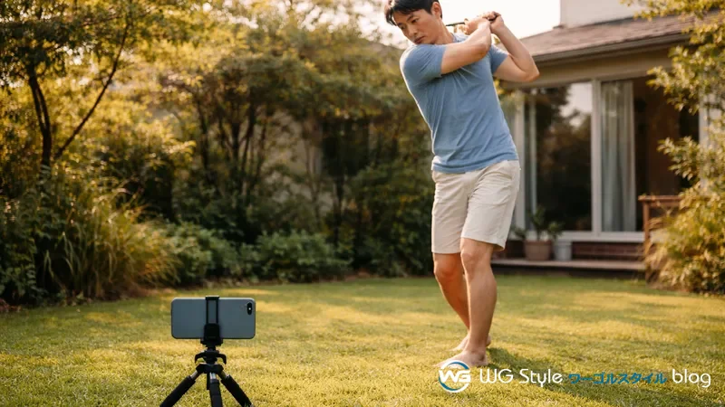 自宅の庭でスマホのミニ三脚を使って素振りのフォームを撮影する30代男性
