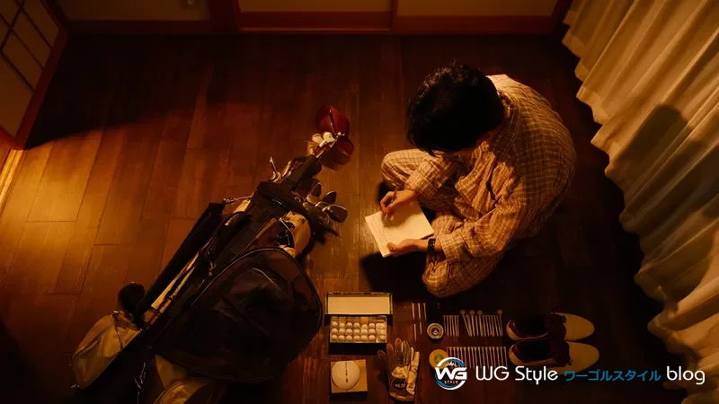 30代日本人男性が前夜にゴルフバッグの周りにラウンド必須アイテムを並べてメモ帳と照合している