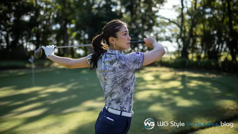 ゴルフコースでクラブを肩の後ろに当てて体幹の回旋ストレッチをする30代女性