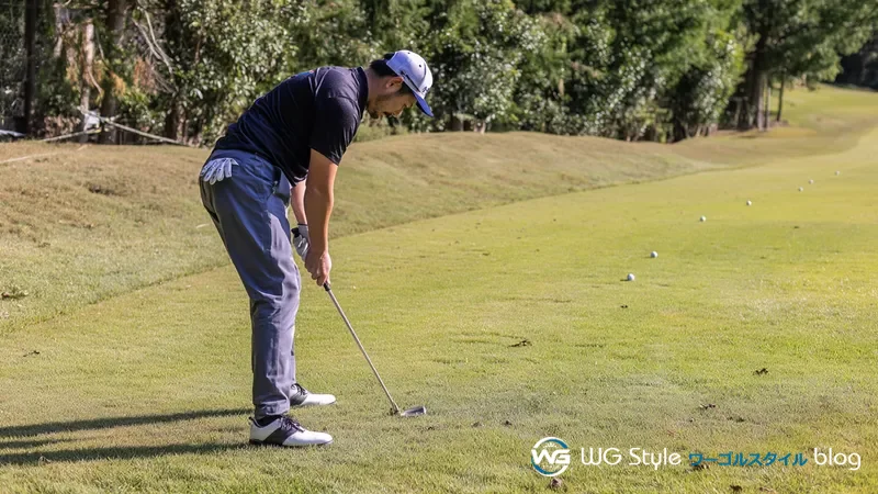 アプローチ練習エリアでチッパーの振り幅を確認しながら距離感を練習する30代男性
