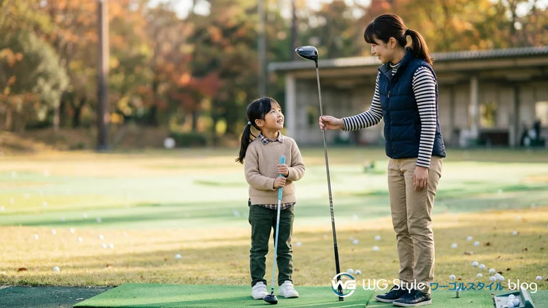 大人用のゴルフクラブと並んで立つ日本人の子ども（長さの違いが分かる）