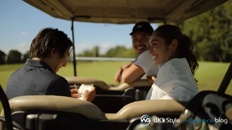 次のホールに向かうゴルフカートの中でスコアカードに記録をつけている30代男性と楽しそうな仲間たち