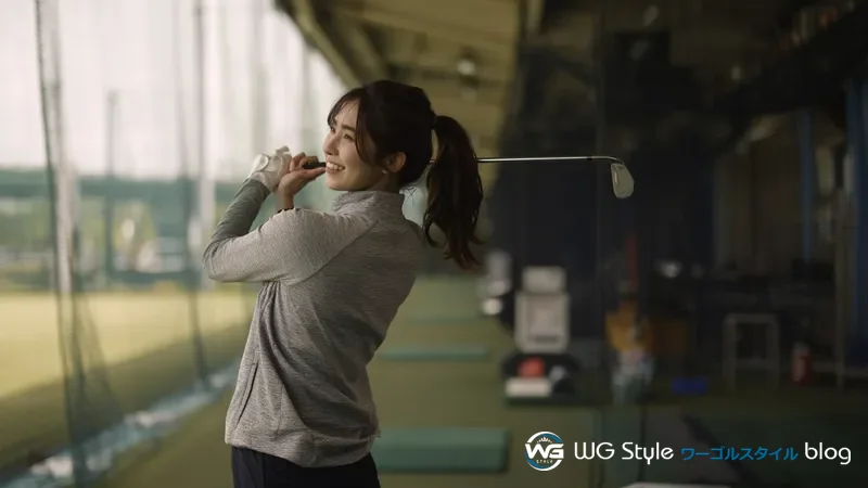 ゴルフ練習場で1人で7番アイアンを打った後のフォロースルーポーズの30代女性